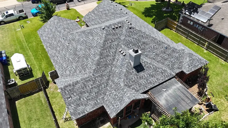 Finished shingle roof on a brick home with a chimney, from above