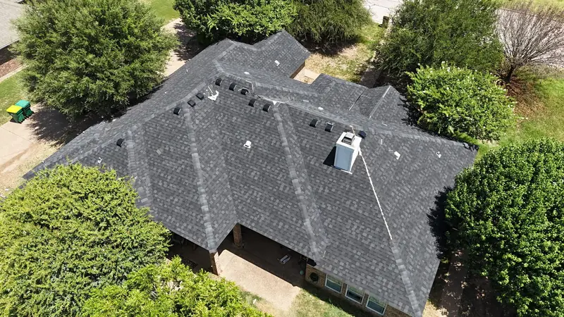 Completed shingle roof surrounded by trees, from above